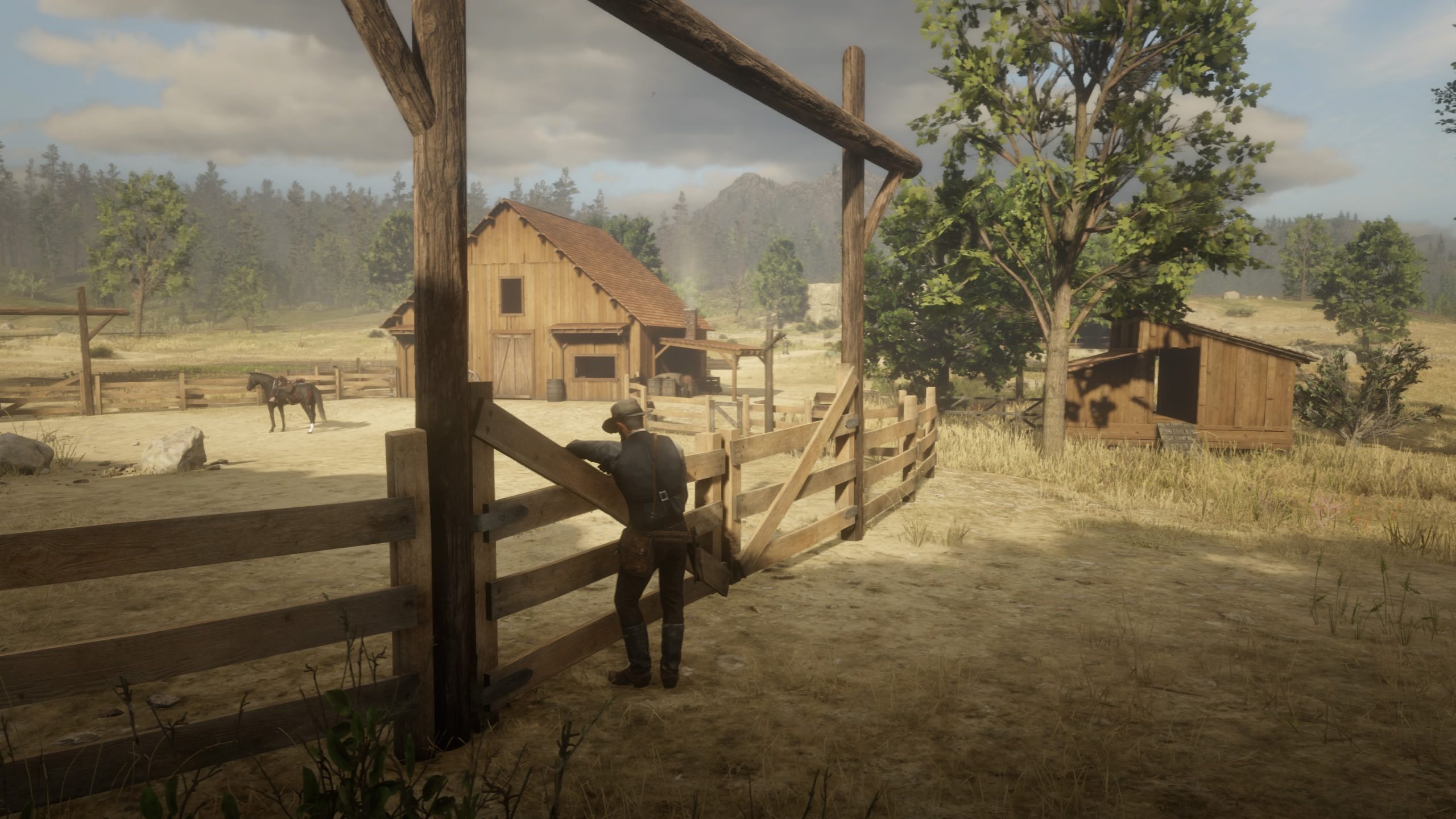 Eine Ranch mit Pferdekoppel, der Spieler lehnt entspannt am Zaun und schaut auf das Anwesen. Im Hintergrund Wald.